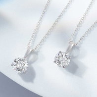 Clear round‑cut diamond white gold pendant necklaces displayed on a white surface.
