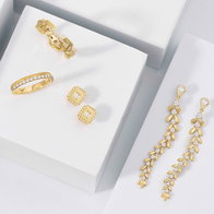 Yellow gold diamond jewelry set featuring a diamond link ring, diamond band, halo diamond stud earrings, and diamond leaf drop earrings on a white display.
