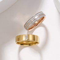 Two diamond accented wedding bands in rose gold and yellow gold displayed on a light background.