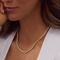 Gold tennis necklace with diamond accents worn on a model.