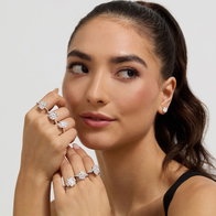 Model’s hands showcasing multiple large diamond engagement rings with diamond stud earrings visible.