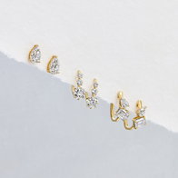 Gold diamond stud earrings in pear, round, and baguette cluster styles arranged in a row.