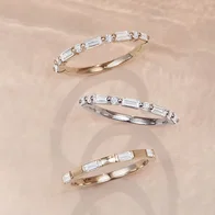 {"en-us":"Three diamond baguette stackable bands in yellow gold and white gold arranged on a neutral background."}